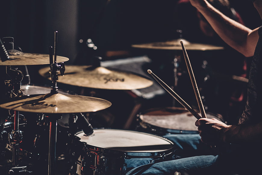 Drummer Playing Drum Kit With Cymbals And Drumsticks In Dark Studio