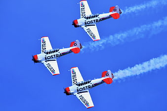Three Eostra stunt planes flying in formation with smoke trails