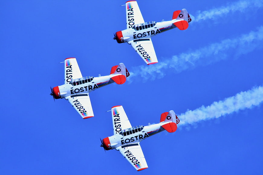 Three Eostra stunt planes flying in formation with smoke trails