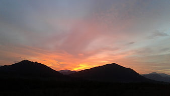 Silhouette of rolling hills against a vibrant sunset sky