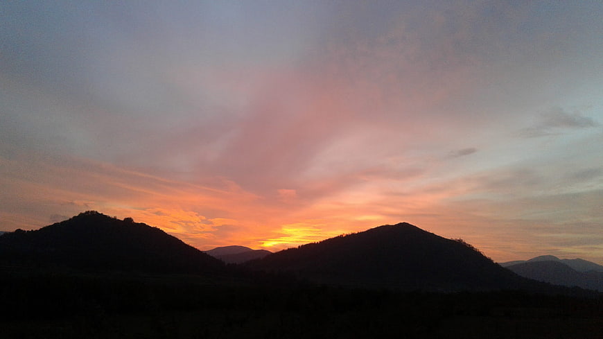 Silhouette of rolling hills against a vibrant sunset sky