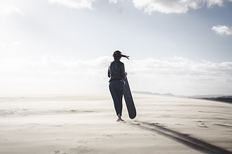 Woman walking on beach with surfboard