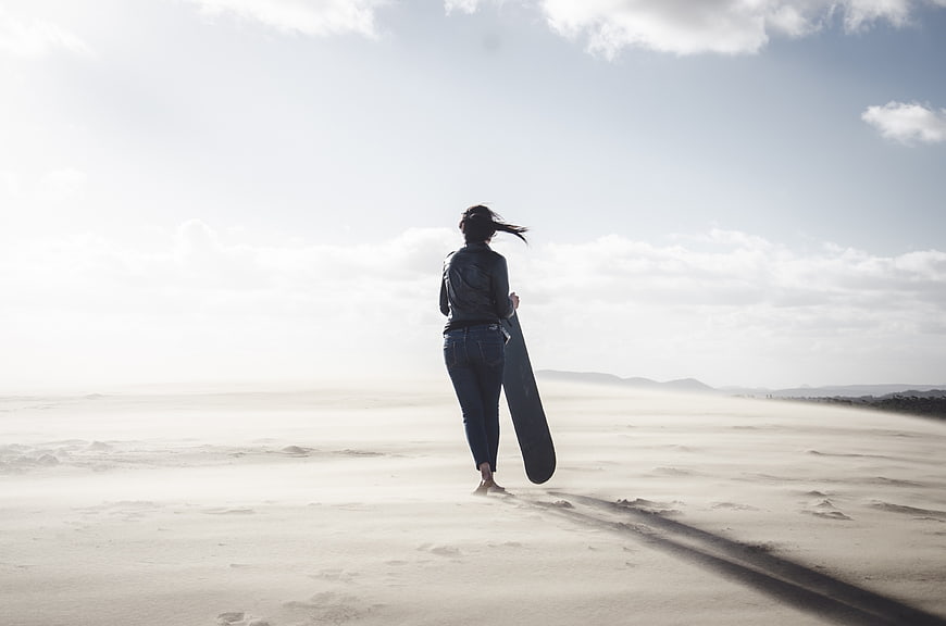 Woman walking on beach with surfboard