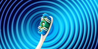 Close-up of a toothbrush head with blue and green bristles on a blue background