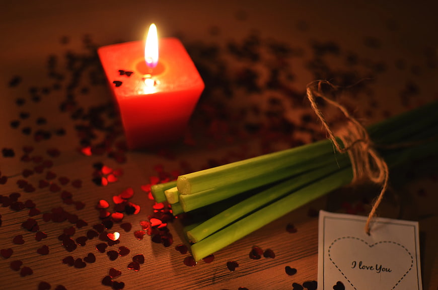 Green onions tied with twine and red candle on wooden table
