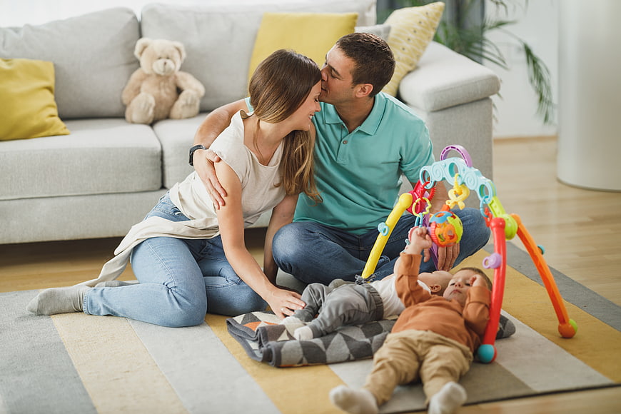 Happy family playing with baby on living room floor