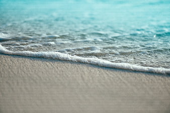 Close-up of gentle ocean waves washing over sandy beach