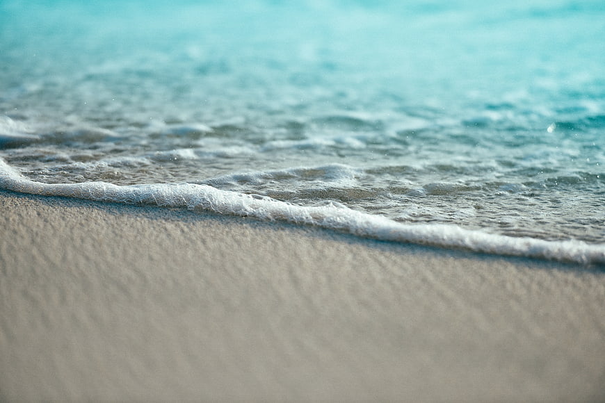 Close-up of gentle ocean waves washing over sandy beach