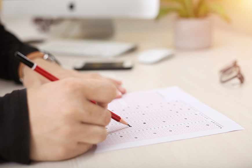 Student Filling Out OMR Exam Sheet With Red Pencil