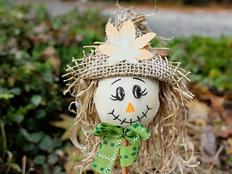 Cute Scarecrow Head with Green Bow in Autumn Garden