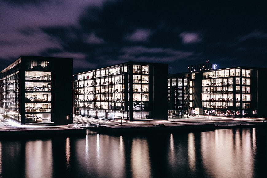 Modern Glass Office Buildings at Night with Water Reflections