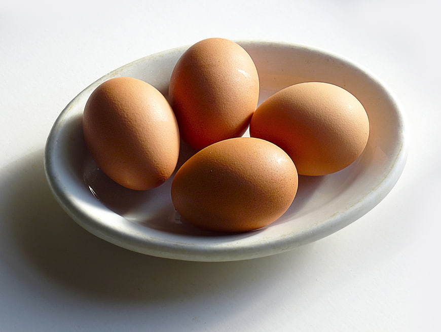 Four Brown Eggs In White Ceramic Bowl On White Background