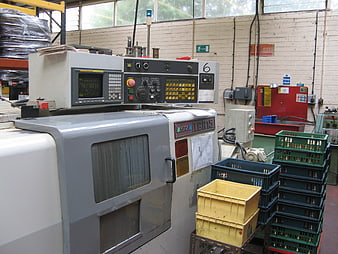 Industrial CNC Machine In Manufacturing Workshop With Plastic Crates