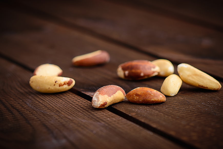 Scattered Brazil Nuts on Dark Wooden Table