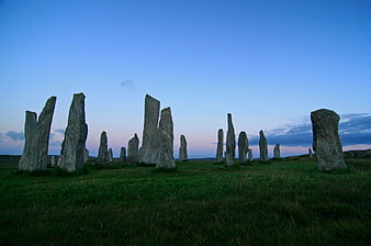 Ancient standing stones in a grassy field at twilight