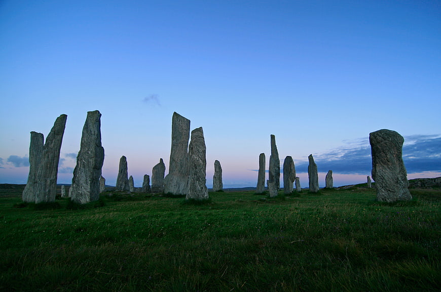 Ancient standing stones in a grassy field at twilight