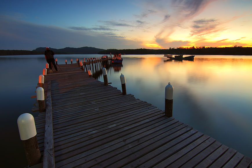 Silhouette of Fisherman on Wooden Pier at Sunset