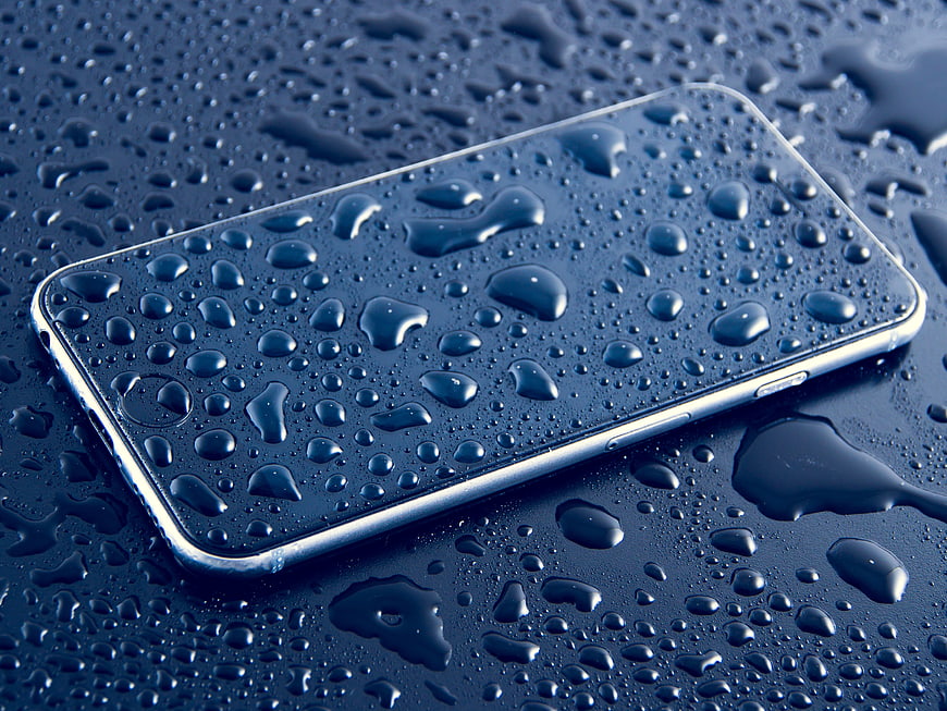 Waterproof Smartphone Covered in Water Droplets on Blue Surface