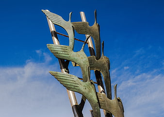 Abstract bronze heron sculpture against blue sky