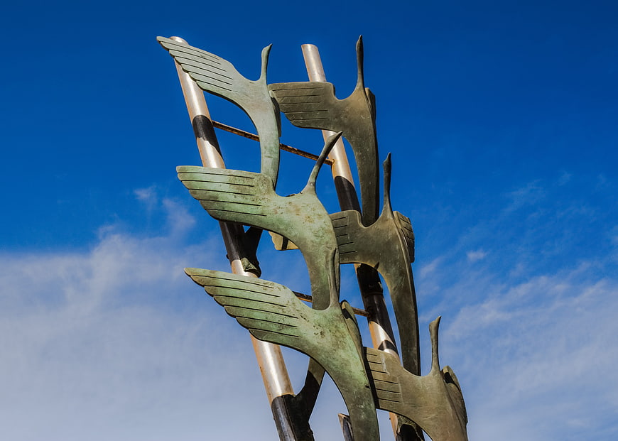 Abstract bronze heron sculpture against blue sky