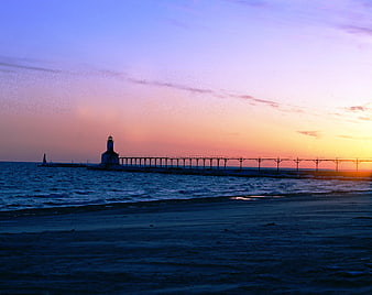 Lighthouse on pier at sunset with colorful sky