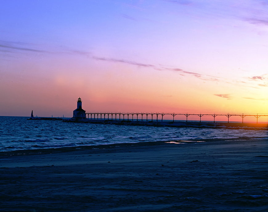 Lighthouse on pier at sunset with colorful sky