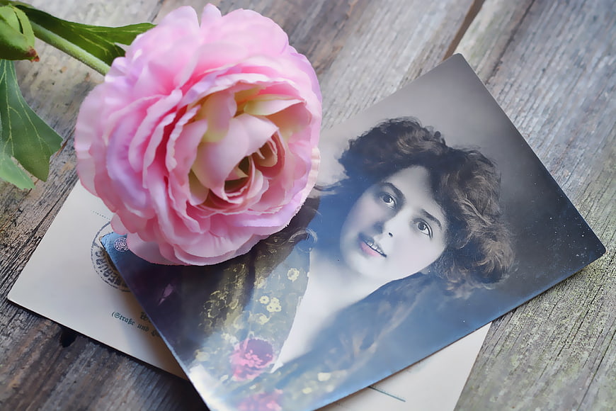 Pink Peony Resting On Vintage Portrait Postcard On Weathered Wood