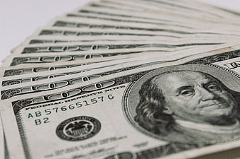 Close-up of fanned hundred dollar bills on white background