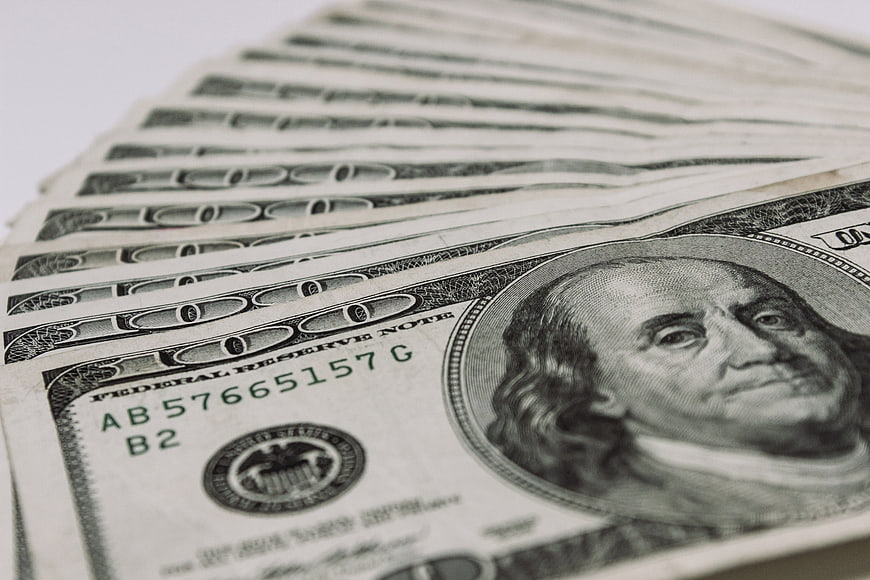 Close-up of fanned hundred dollar bills on white background