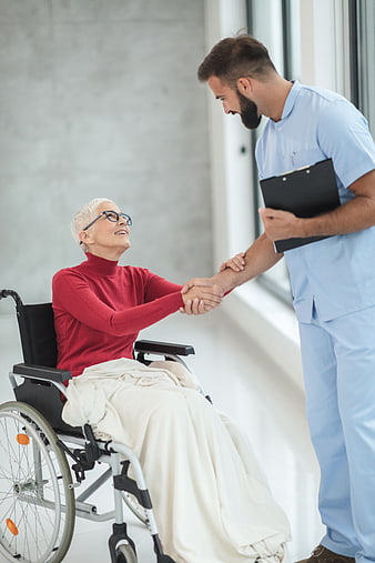 Male Nurse Holding Hands with Senior Woman in Wheelchair