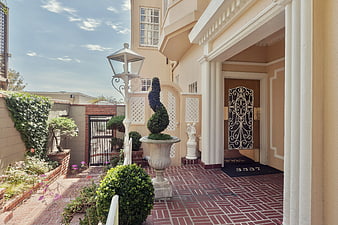 Elegant Mediterranean Home Entrance with Brick Patio and Topiary