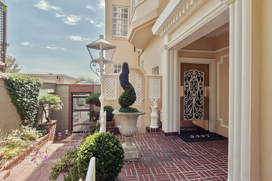 Elegant Mediterranean Home Entrance with Brick Patio and Topiary