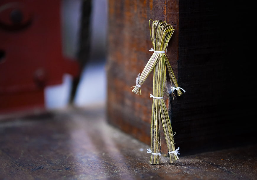 Straw Doll Figurine Leaning Against Wooden Box