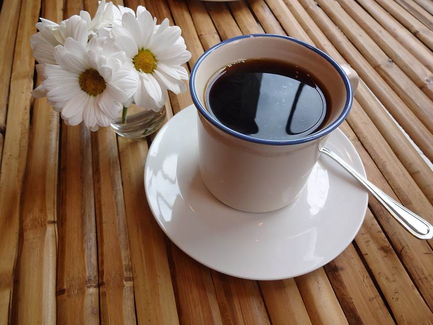 White Coffee Cup with Daisies on Bamboo Table