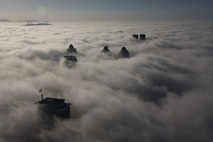 City skyscrapers emerging from thick sea of fog