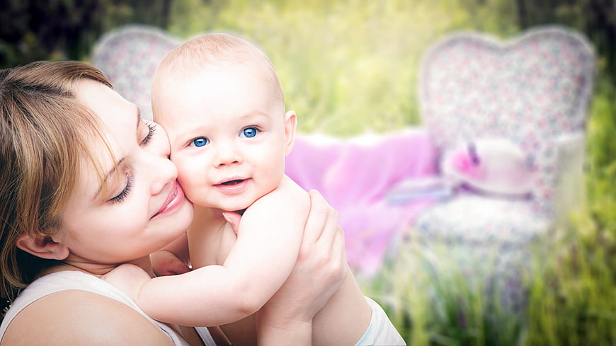 Mother Holding Smiling Baby In Garden With Heart Bench