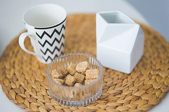 Brown sugar cubes in glass bowl with mug and milk jug