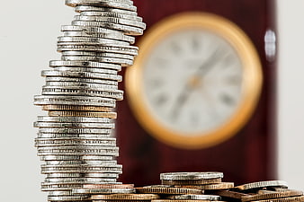 Stack of coins with blurred clock background