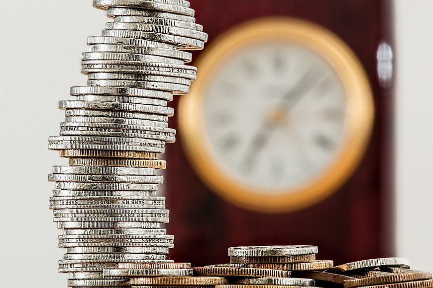 Stack of coins with blurred clock background