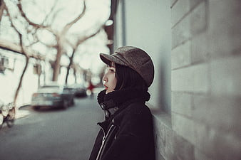 Woman in Cap Leaning Against Wall on Street