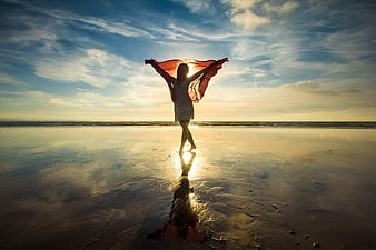 Silhouette of woman with red scarf on beach at sunset