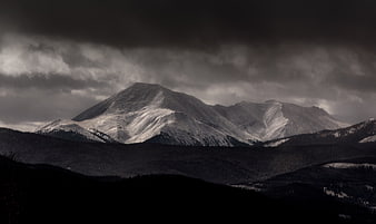 Dramatic Snow-Capped Mountain Peak Under Dark Stormy Clouds