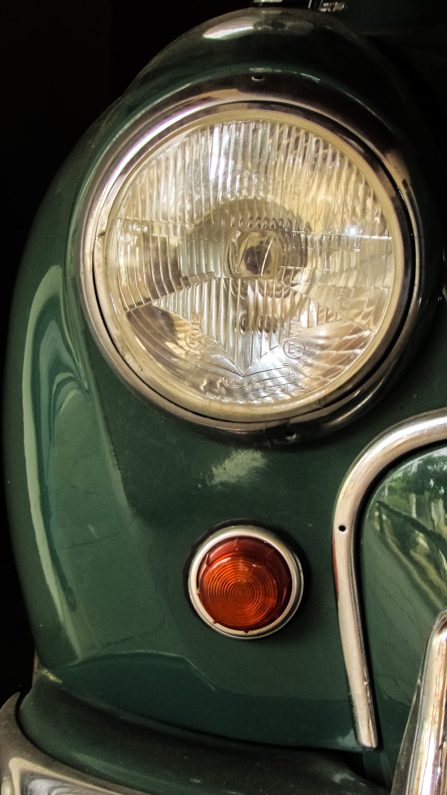 Close-up of vintage green car headlight and turn signal