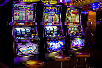 Row of Neon Slot Machines in Dark Casino