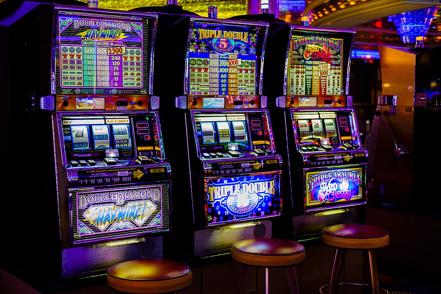 Row of Neon Slot Machines in Dark Casino