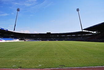 Empty Soccer Stadium with Green Pitch and Blue Seats