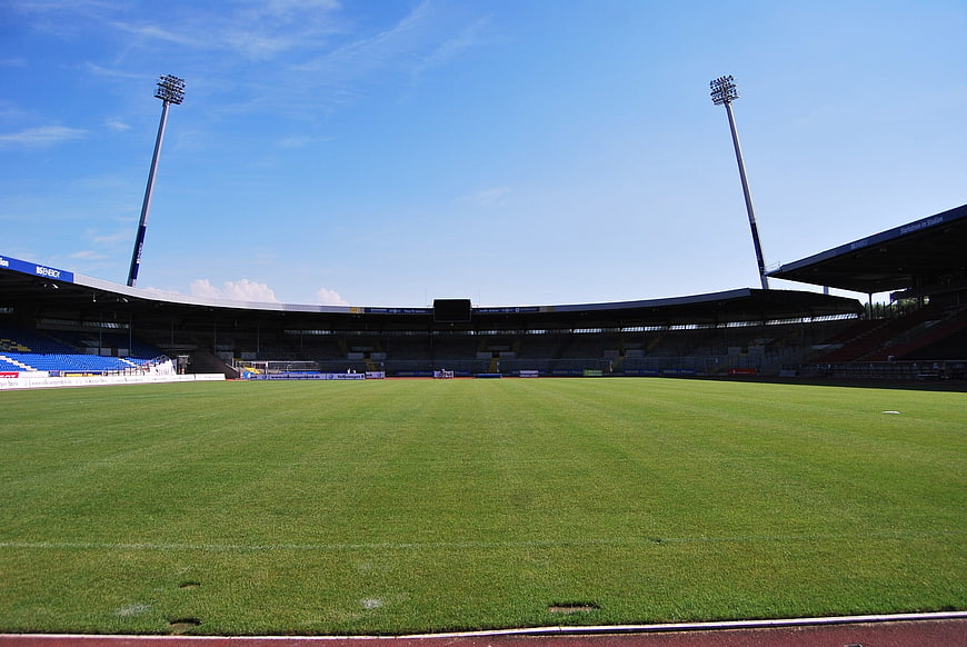 Empty Soccer Stadium with Green Pitch and Blue Seats