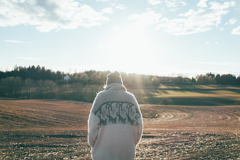 Person in white sweater looking at sunny winter landscape