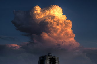 Dramatic golden cumulus cloud over city building at sunset