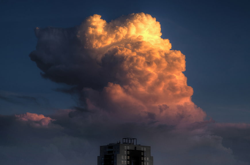 Dramatic golden cumulus cloud over city building at sunset